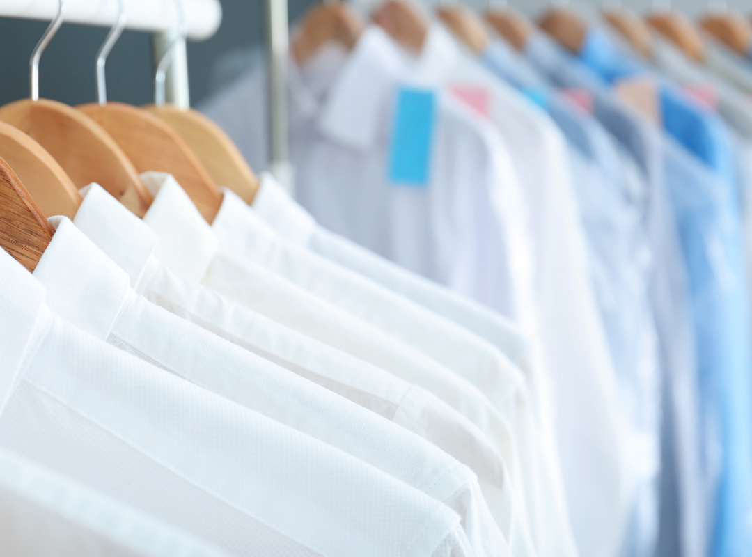 Freshly laundered white and blue dress shirts on wooden hangers at a dry cleaning facility — dry cleaning pickup and delivery service in West Islip