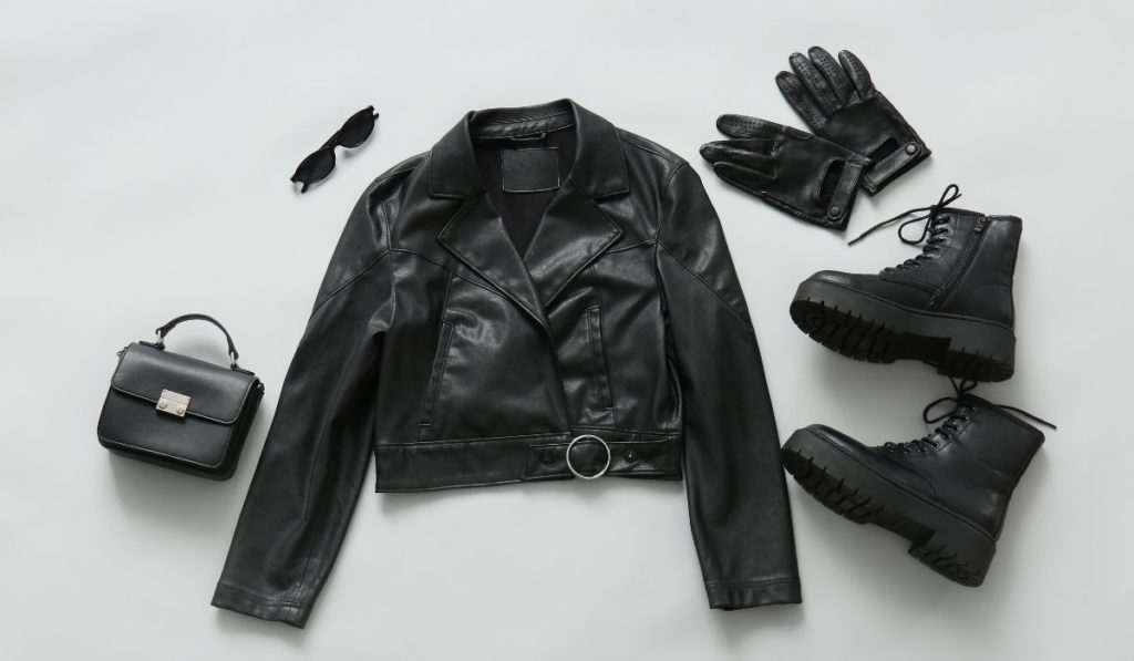 Black leather jacket, boots, gloves, and handbag flat lay - leather items that benefit from professional leather cleaning service on Long Island