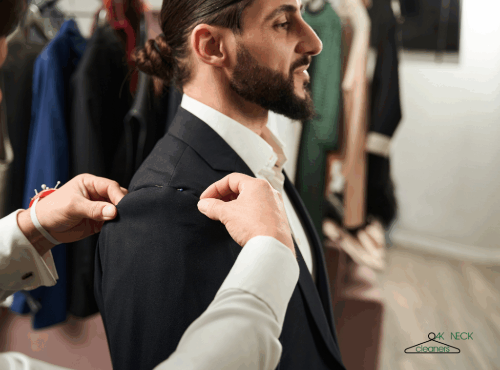 Tailor pinning the shoulder of a navy suit jacket during a fitting - professional suit alterations service on Long Island