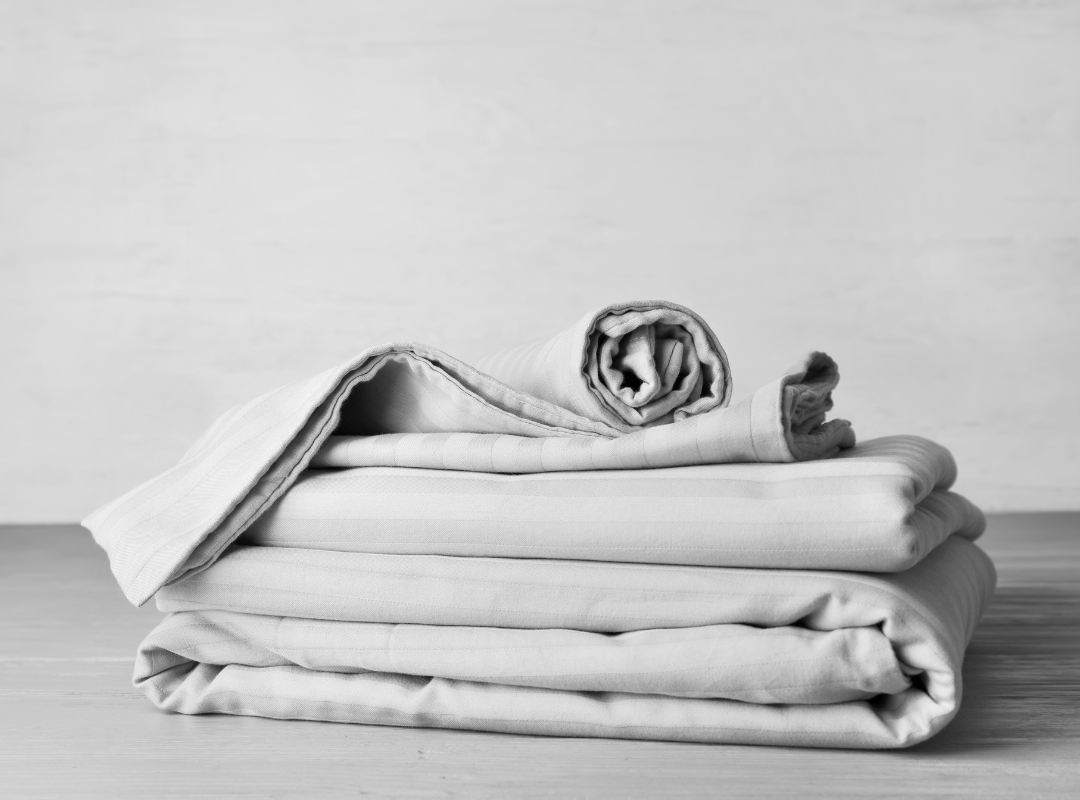 Neatly folded and rolled white table linens stacked on a wooden surface — professional table linen cleaning service on Long Island